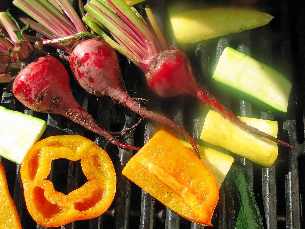 Remolachas y calabacitas recién cortadas sobre la parrilla encendida.