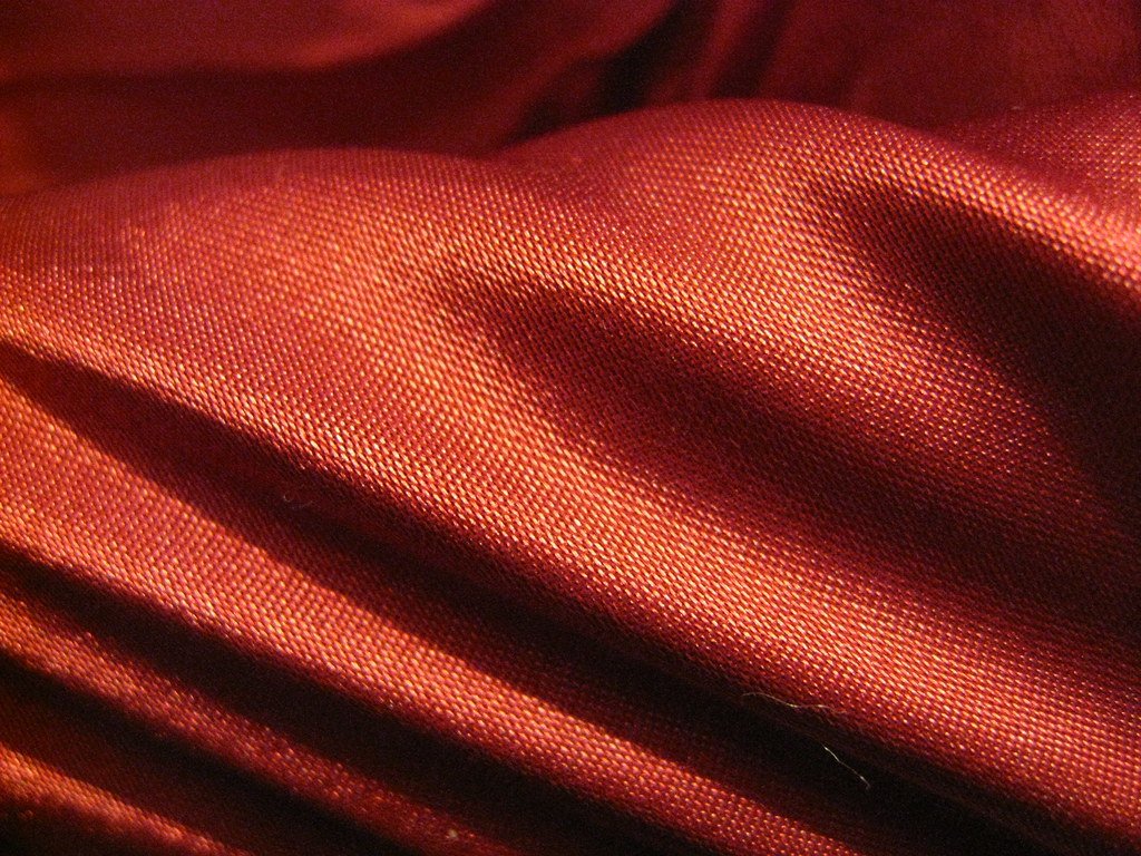Tela roja plegada en capas, textura de seda con pliegues