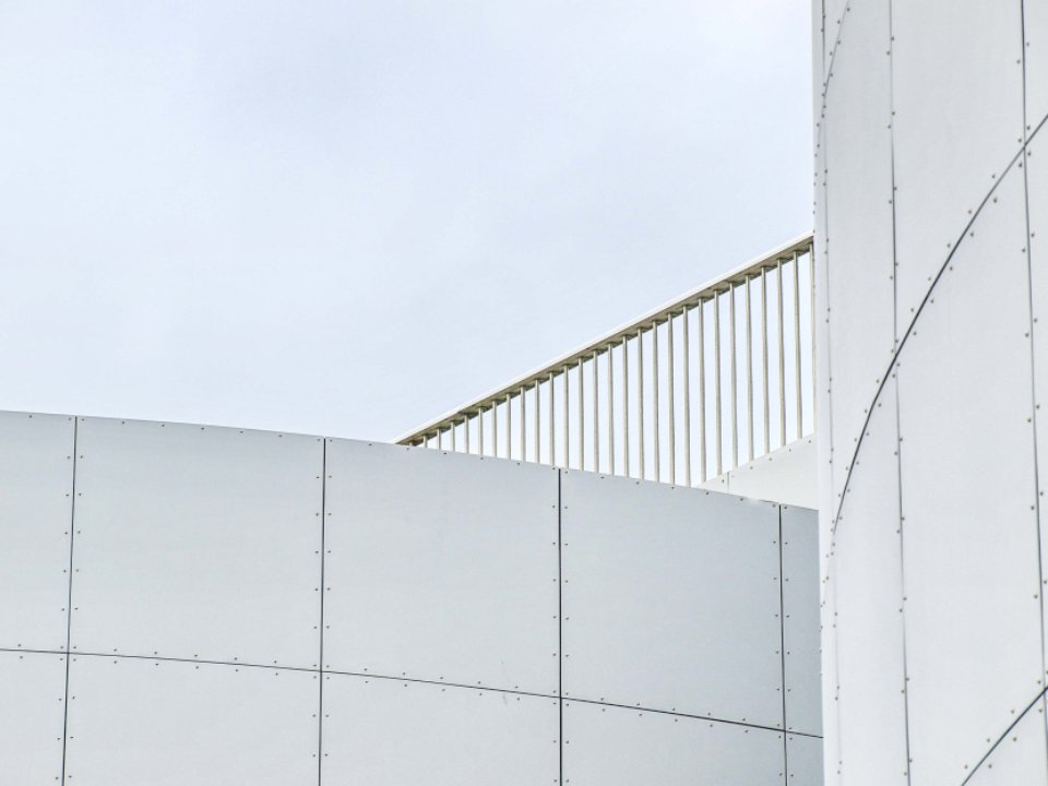 Nave logística con revestimiento metálico azul y blanco, andenes de carga y camiones estacionados