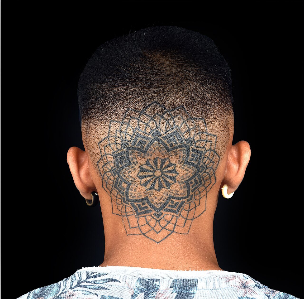 Mandala en dotwork tatuado en la nuca, puntillismo denso sobre fondo negro
