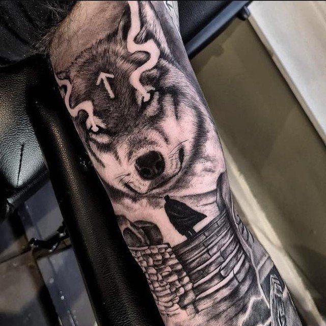 Retrato realista de un lobo en negro y gris sobre el antebrazo
